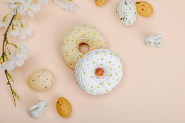 Kiraz dallarıyla örülmüş el yapımı çörekler. Bayramlık Paskalya, tebrik kartı, yaratıcı zanaat konsepti. Moda kayısı arka planı, düz yatış, üst görünüm