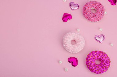 Parlak kalpli el yapımı örülü çörekler. Sevgililer Günü ya da Anneler Günü, tebrik kartı, yaratıcı sanatlar konsepti. Pembe zemin, düz yatış, üst görünüm