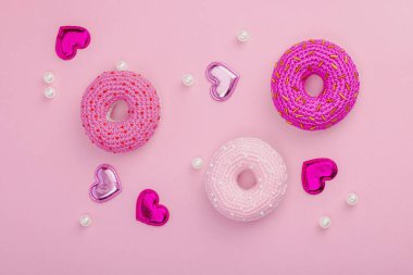 Parlak kalpli el yapımı örülü çörekler. Sevgililer Günü ya da Anneler Günü, tebrik kartı, yaratıcı sanatlar konsepti. Pembe zemin, düz yatış, üst görünüm