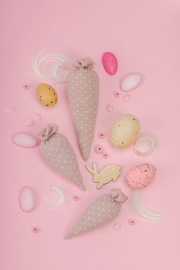 El yapımı Paskalya konsepti. Geleneksel dekorasyonlu tekstil havuçları dikmek. Kutlama sembolleri, tebrik kartları, düz yatış. Yaratıcı zanaat konsepti, pastel pembe arkaplan, üst görünüm