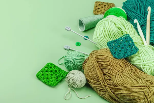 A set of knitting yarn and tools in spring colors. Handmade concept, creative art, crafting process. Hobby, relax, lifestyle, flat lay on pastel green background, copy space