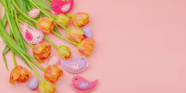Nazik Paskalya kompozisyonu lale çiçekleri ve el yapımı keçeli kuşlar. Geleneksel dekoratif unsurlar, tebrik kartı. Düz konum, pembe arkaplan, pankart biçimi