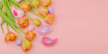 Nazik Paskalya kompozisyonu lale çiçekleri ve el yapımı keçeli kuşlar. Geleneksel dekoratif unsurlar, tebrik kartı. Düz konum, pembe arkaplan, pankart biçimi