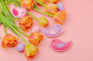 Nazik Paskalya kompozisyonu lale çiçekleri ve el yapımı keçeli kuşlar. Geleneksel dekoratif unsurlar, tebrik kartı. Düz yatış, pembe arkaplan, üst görünüm