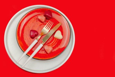 Çikolata şekerli minimalist bahar sofrası. Geleneksel bayram sembolü, tebrik kartı, düz yatak. Tutku kırmızı arkaplan, üst görünüm