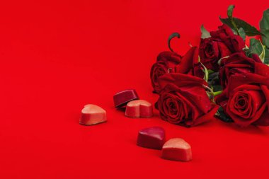 Minimalist bahar tebrik kartı içinde çikolata şekeri ve güller var. Geleneksel bayram sembolü, düz yatış. Tutku kırmızı arkaplan, boşluğu kopyala