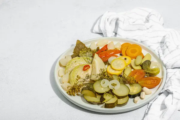 Assorted fermented vegetables. Probiotics, healthy food, vitamins. Vegan lifestyle, pickled dish. Flat lay, light stone concrete background. Hard light, dark shadow, copy space