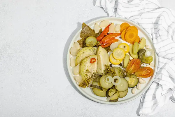 Assorted fermented vegetables. Probiotics, healthy food, vitamins. Vegan lifestyle, pickled dish. Flat lay, light stone concrete background. Hard light, dark shadow, top view