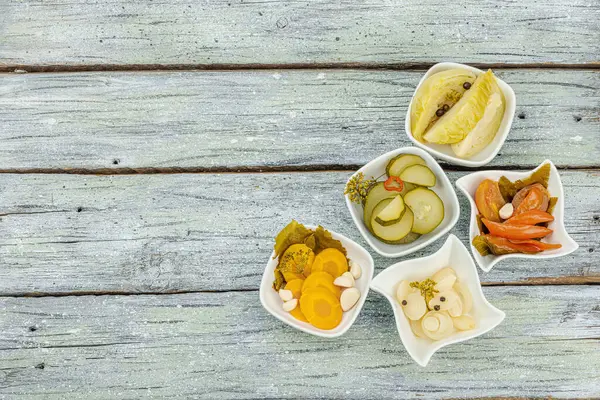 Assorted fermented vegetables. Probiotics, healthy food, vitamins. Vegan lifestyle, pickled dish. Flat lay, vintage wooden background, top view