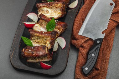 Baharatlı, sebzeli ve soslu domuz pirzolası. Mangal partisi için geleneksel malzeme, piknik konsepti. Jöleli et, keten peçete, son moda tabaklar. Siyah taş arkaplan, üst görünüm