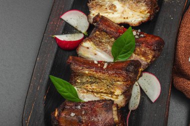 Baharatlı, sebzeli ve soslu domuz pirzolası. Mangal partisi için geleneksel malzeme, piknik konsepti. Jöleli et, keten peçete, son moda tabaklar. Siyah taş arkaplan, üst görünüm