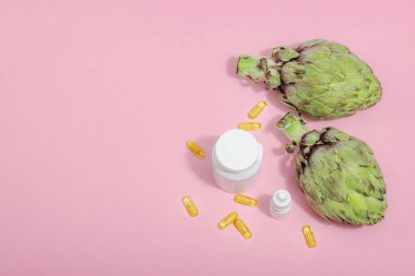 Beslenme takviyeleri enginar yaprağı özü kapsülleri. Alternatif tıp, güzellik bitkisel yaşam tarzı, sağlıklı kişisel bakım. Sert ışık, koyu gölge, pembe arkaplan, düz yatış, üst manzara