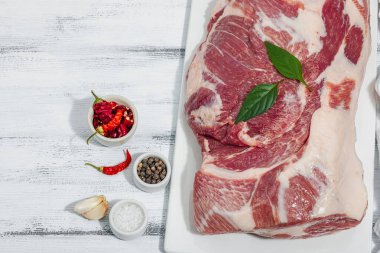 Çiğ domuz eti. Yemek pişirmek için geleneksel malzemeler. Sarımsaklı karanfil, taze maydanoz. Moda duruşu, beyaz arkaplan, düz konum, üst görünüm
