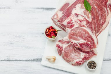 Çiğ domuz eti. Yemek pişirmek için geleneksel malzemeler. Sarımsaklı karanfil, taze maydanoz. Moda duruşu, beyaz arkaplan, düz konum, üst görünüm