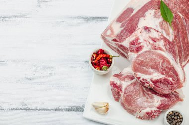 Çiğ domuz eti. Yemek pişirmek için geleneksel malzemeler. Sarımsaklı karanfil, taze maydanoz. Moda duruşu, beyaz arkaplan, düz konum, üst görünüm