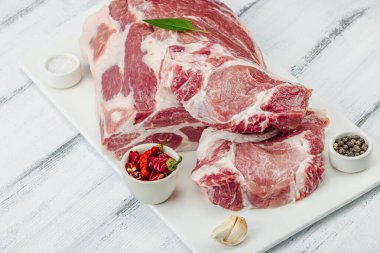 Çiğ domuz eti. Yemek pişirmek için geleneksel malzemeler. Sarımsaklı karanfil, taze maydanoz. Moda duruşu, beyaz arkaplan, düz yatış, kopyalama alanı