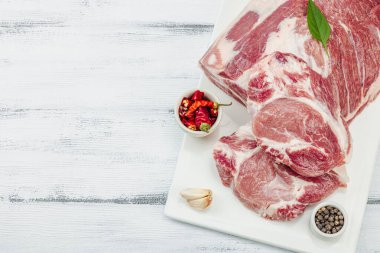 Çiğ domuz eti. Yemek pişirmek için geleneksel malzemeler. Sarımsaklı karanfil, taze maydanoz. Moda duruşu, beyaz arkaplan, düz konum, üst görünüm