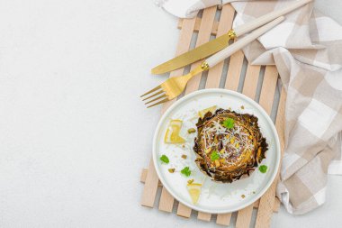 Parmesan peyniri ve şam fıstıklı enfes pişmiş enginar. Zeytinyağı, sarımsak, maydanoz ve limon. Beyaz ahşap arka plan, vejetaryen yemeği yemeye hazır, üst manzara.