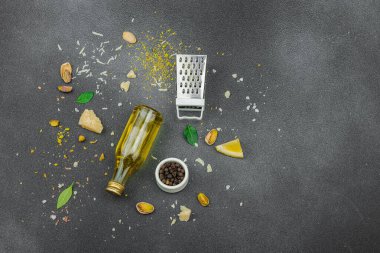 Mutfak arka planı siyah tonlarda. Yemek pişirme konsepti, çatal bıçak, rende, peynir, limon, fıstık ve yeşillik. Düz yatış, sağlıklı yaşam tarzı, üst görünüm