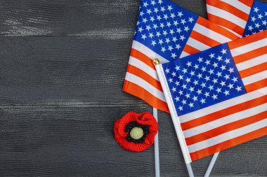 Hafıza Günü konsepti. Amerika Birleşik Devletleri bayrakları ve el yapımı gelincik çiçeği. Geleneksel semboller, düz döşeme, siyah ahşap zemin, üst görünüm