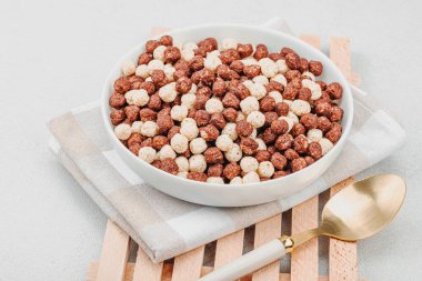 Kakao ve vanilya şeklinde kepekli vejetaryen gevrekleri. Dolu kâse yemeye hazır, sağlıklı kahvaltı konsepti, günaydın tarzı. Beyaz taş arkaplan, kopyalama alanı