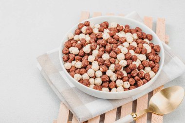 Kakao ve vanilya şeklinde kepekli vejetaryen gevrekleri. Dolu kâse yemeye hazır, sağlıklı kahvaltı konsepti, günaydın tarzı. Beyaz taş arkaplan, kopyalama alanı