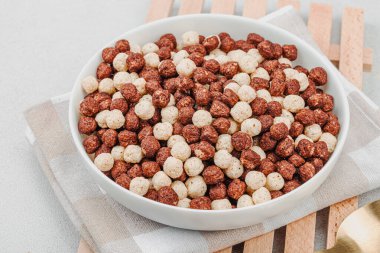 Kakao ve vanilya şeklinde kepekli vejetaryen gevrekleri. Dolu kâse yemeye hazır, sağlıklı kahvaltı konsepti, günaydın tarzı. Beyaz taş beton arka plan, kapat