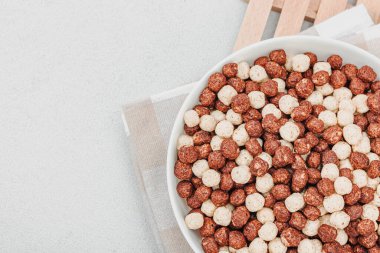 Kakao ve vanilya şeklinde kepekli vejetaryen gevrekleri. Dolu kâse yemeye hazır, sağlıklı kahvaltı konsepti, günaydın tarzı. Beyaz taş arkaplan, üst görünüm