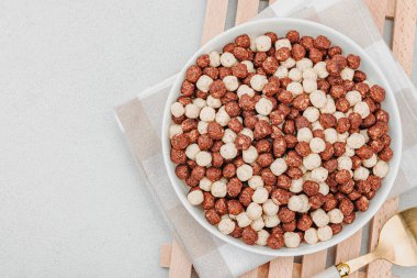 Kakao ve vanilya şeklinde kepekli vejetaryen gevrekleri. Dolu kâse yemeye hazır, sağlıklı kahvaltı konsepti, günaydın tarzı. Beyaz taş arkaplan, üst görünüm