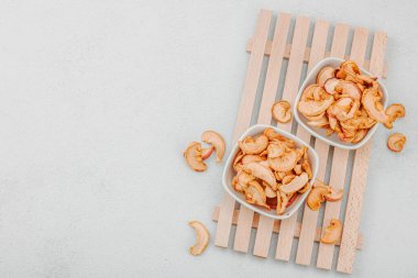 Kuru elma parçalarını kaseye koy. Sağlıklı beslenme, vejetaryen yaşam tarzı, kilo verme konsepti. Beyaz taş arkaplan, üst görünüm