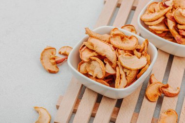 Kuru elma parçalarını kaseye koy. Sağlıklı beslenme, vejetaryen yaşam tarzı, kilo verme konsepti. Beyaz taş arkaplan, kopyalama alanı