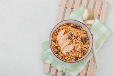 Lezzetli tahıl gevreği ve kurutulmuş meyveli vejetaryen kasesi. Yemek yemeye hazır, sağlıklı kahvaltı konsepti, günaydın tarzı. Beyaz taş arkaplan, üst görünüm