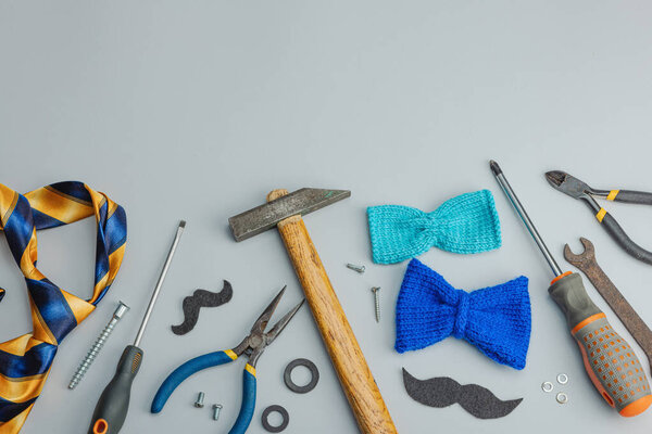 Концепция Дня отца. Набор ручных инструментов, галстук, запчасти, традиционные символы. Открытка, плоский уголок, серый фон, вид сверху