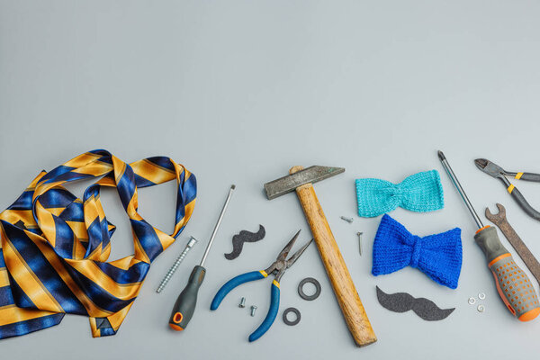 Концепция Дня отца. Набор ручных инструментов, галстук, запчасти, традиционные символы. Открытка, плоский уголок, серый фон, вид сверху