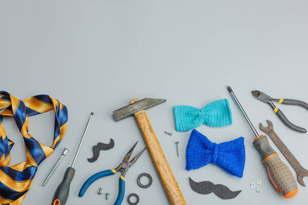 Концепция Дня отца. Набор ручных инструментов, галстук, запчасти, традиционные символы. Открытка, плоский уголок, серый фон, вид сверху