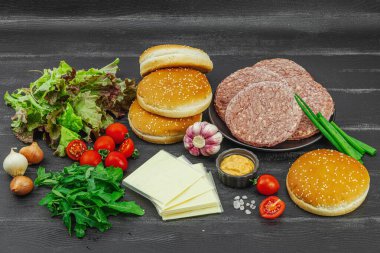 Hamburger köftesi. Sığır pirzolası, çörek, sebze ve sos. Ev yapımı Amerikan klasiği, geleneksel piknik, parti ya da Bağımsızlık Günü yemekleri. Koyu tahta arkaplan, boşluğu kopyala