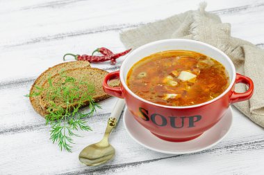 Masada sosisli, zeytinli ve sebzeli et solyanka çorbası. Geleneksel Doğu Avrupa yemeği, ekmek, çatal bıçak takımı, eski peçete. Rustik biçim, tahta tahta tahta arka plan, kopyalama alanı