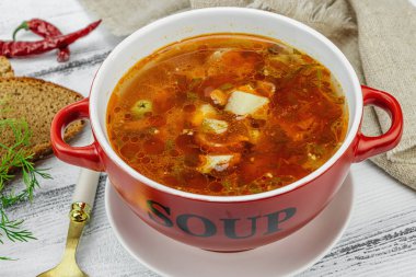 Masada sosisli, zeytinli ve sebzeli et solyanka çorbası. Geleneksel Doğu Avrupa yemeği, ekmek, çatal bıçak takımı, eski peçete. Kırsal stil, tahta kaplama arka plan, kapat