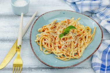 Domates soslu, otlu ve peynirli makarna. Sağlıklı vejetaryen yemekleri yemeye hazır, porsiyon ahşap masada servis ediliyor. Pastel deniz usulü, düz yatış, yakın çekim.