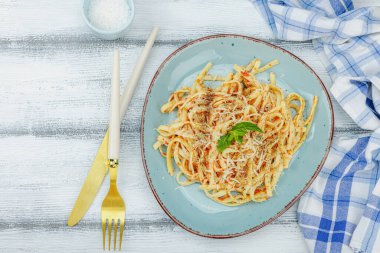 Domates soslu, otlu ve peynirli makarna. Sağlıklı vejetaryen yemekleri yemeye hazır, porsiyon ahşap masada servis ediliyor. Pastel deniz tarzı, düz yatış, üst manzara