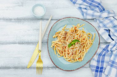 Domates soslu, otlu ve peynirli makarna. Sağlıklı vejetaryen yemekleri yemeye hazır, porsiyon ahşap masada servis ediliyor. Pastel deniz tarzı, düz yatış, üst manzara