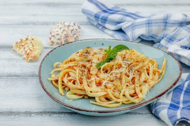 Domates soslu, otlu ve peynirli makarna. Sağlıklı vejetaryen yemekleri yemeye hazır, porsiyon ahşap masada servis ediliyor. Pastel deniz usulü, düz yatış, yakın çekim.