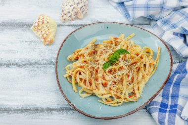 Domates soslu, otlu ve peynirli makarna. Sağlıklı vejetaryen yemekleri yemeye hazır, porsiyon ahşap masada servis ediliyor. Pastel deniz tarzı, düz döşeme, kopyalama alanı