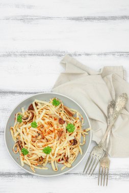 Domates soslu makarna, yenilebilir mantar, otlar ve kırmızı biber. Sağlıklı vejetaryen yemekleri yemeye hazır, porsiyon ahşap masada servis ediliyor. Kırsal stil, düz yatış, üst görünüm