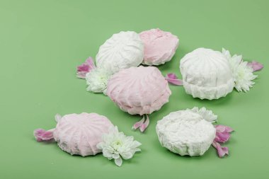 Pastel yeşil arka planda taze çiçek yapraklı meyveli marşmelov. Laktozsuz vejetaryen tatlı, sağlıklı yaşam tarzı, düz yatış, fotokopi alanı