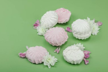 Pastel yeşil arka planda taze çiçek yapraklı meyveli marşmelov. Laktozsuz vejetaryen tatlı, sağlıklı yaşam tarzı, düz yatış, fotokopi alanı