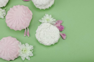 Pastel yeşil arka planda taze çiçek yapraklı meyveli marşmelov. Laktozsuz vejetaryen tatlı, sağlıklı yaşam tarzı, düz yatış, üst görünüm