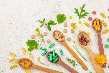 Bitki bazlı takviyeler, taze otlar ve çiçeklerle birlikte doğal vitaminler. Organik maddeler, bütünsel sağlık kavramlarını, alternatif yaşam tarzını öneriyor. Işık taşı arkaplan, üst görünüm