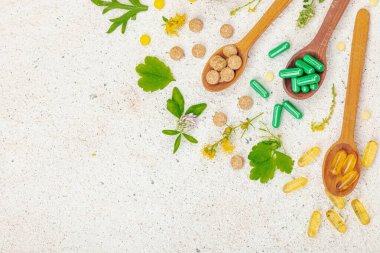 Bitki bazlı takviyeler, taze otlar ve çiçeklerle birlikte doğal vitaminler. Organik maddeler, bütünsel sağlık kavramlarını, alternatif yaşam tarzını öneriyor. Işık taşı arkaplan, üst görünüm