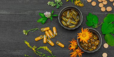 Bitki bazlı takviyeler, taze otlar ve çiçeklerle birlikte doğal vitaminler. Organik ilaçlar bütünsel sağlık kavramlarını, alternatif yaşam tarzını öneriyor. Koyu tahta arkaplan, pankart biçimi